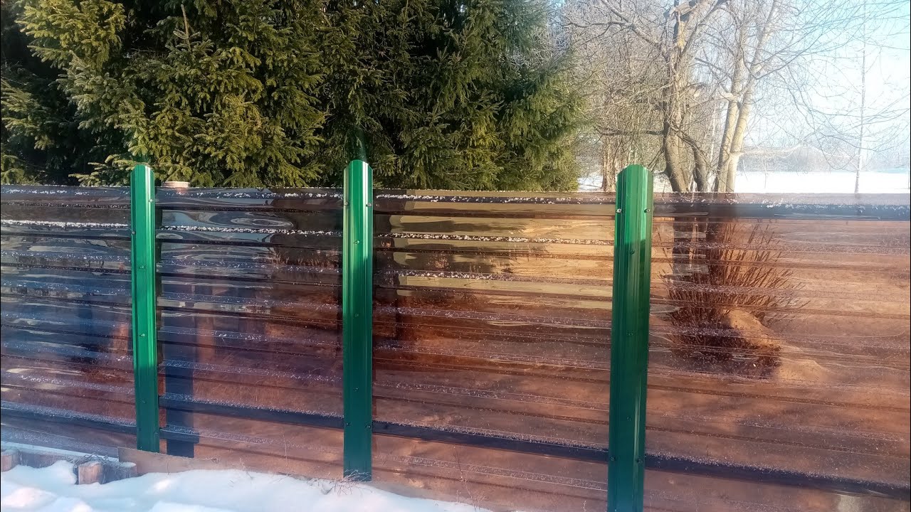 Забор из монолитного поликарбоната с зелеными столбами