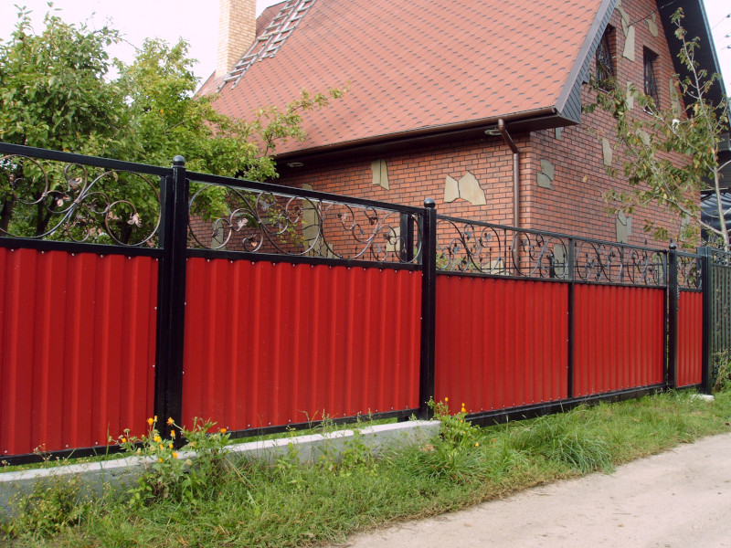 Красный забор с коваными элементами